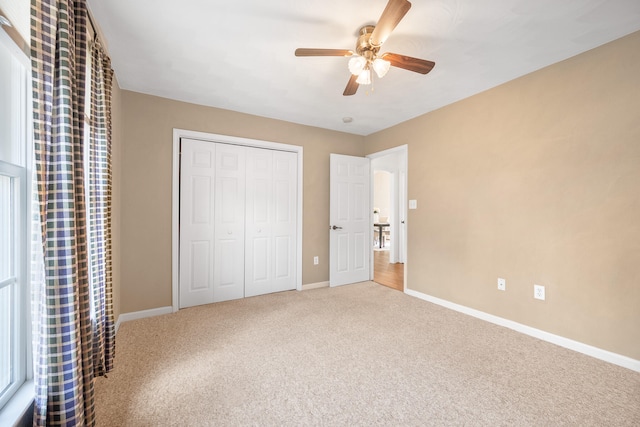 unfurnished bedroom featuring a ceiling fan, carpet, baseboards, and a closet