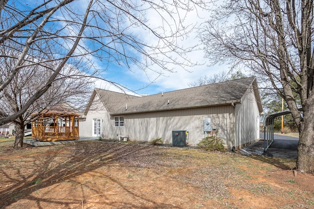 back of house featuring a deck, a gazebo, roof with shingles, a detached carport, and central AC unit