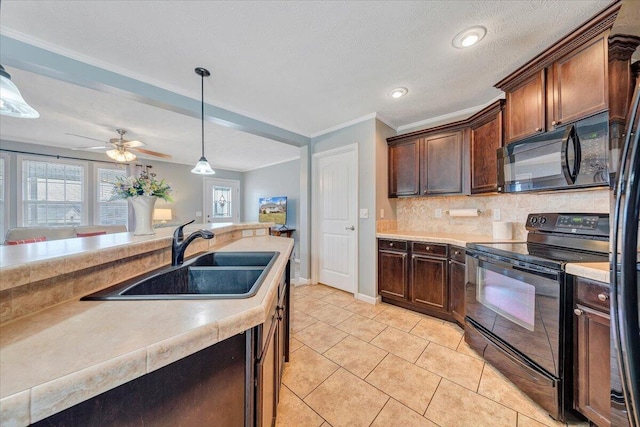 kitchen featuring a sink, black appliances, light countertops, pendant lighting, and backsplash