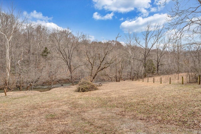 view of yard featuring a forest view and fence