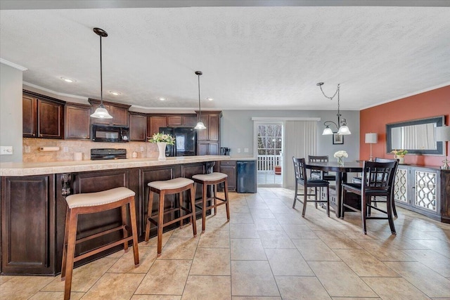 kitchen featuring black appliances, light countertops, dark brown cabinets, crown molding, and backsplash