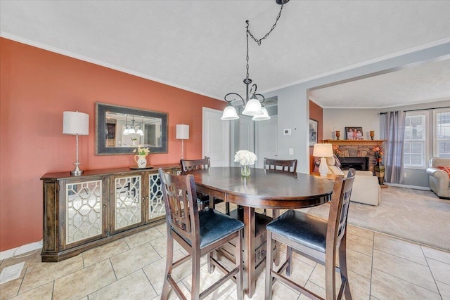 dining area with visible vents, light carpet, a fireplace, crown molding, and baseboards