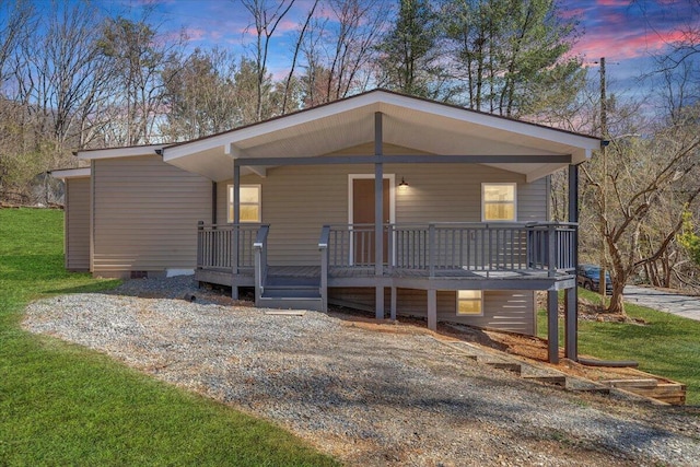 view of front of house featuring gravel driveway, a front yard, and covered porch