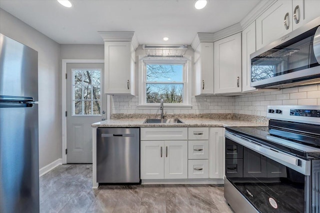 kitchen featuring baseboards, a sink, stainless steel appliances, white cabinets, and backsplash