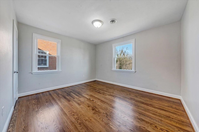 spare room with visible vents, baseboards, and wood finished floors