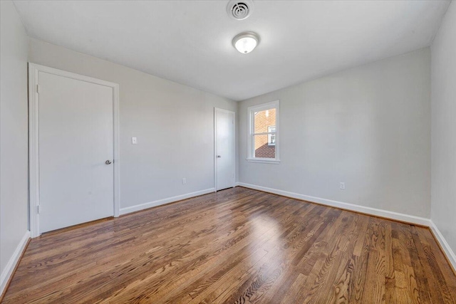 unfurnished room featuring visible vents, baseboards, and wood finished floors