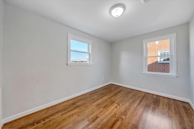 spare room featuring baseboards and wood finished floors