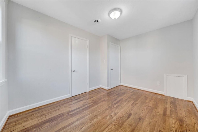 spare room featuring wood finished floors, visible vents, and baseboards