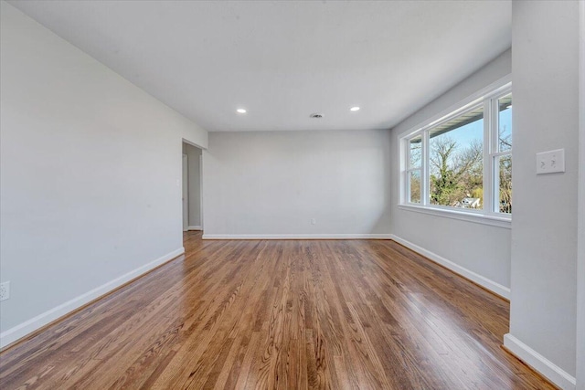 unfurnished room with recessed lighting, wood finished floors, and baseboards