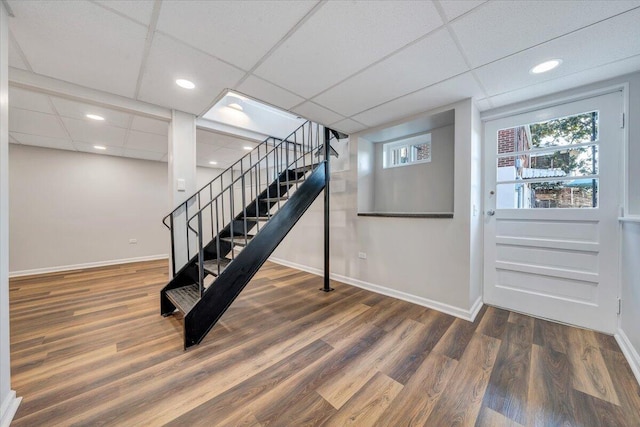 stairway with recessed lighting, wood finished floors, baseboards, and a paneled ceiling