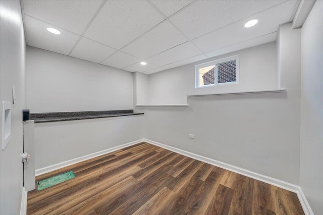 basement featuring recessed lighting, a paneled ceiling, baseboards, and wood finished floors