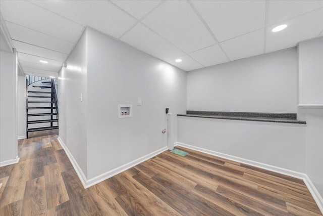 finished basement with stairway, wood finished floors, baseboards, recessed lighting, and a paneled ceiling