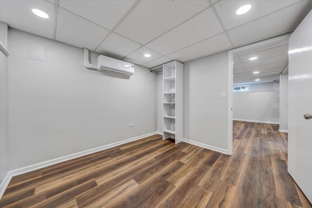 finished below grade area featuring a wall unit AC, recessed lighting, baseboards, and dark wood-style flooring