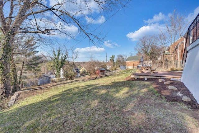 view of yard with a storage shed, an outdoor structure, a deck, and fence