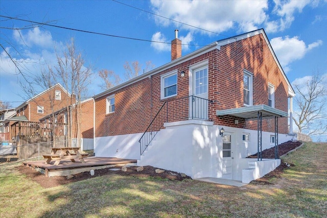 back of house featuring a yard, brick siding, and a chimney