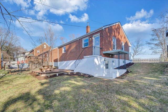 back of property with brick siding, a chimney, and a yard