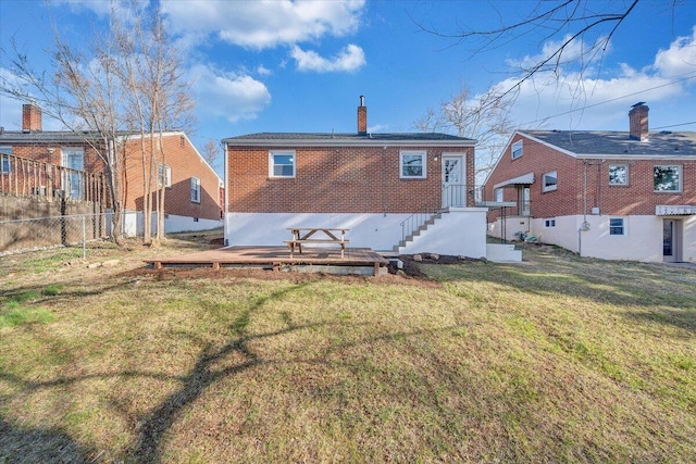 rear view of property with a chimney, fence, brick siding, and a lawn