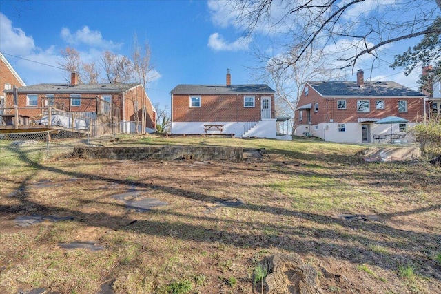 rear view of house with a chimney, fence, brick siding, and a lawn