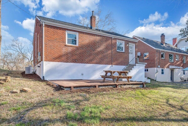 back of property with a yard, brick siding, a chimney, and entry steps