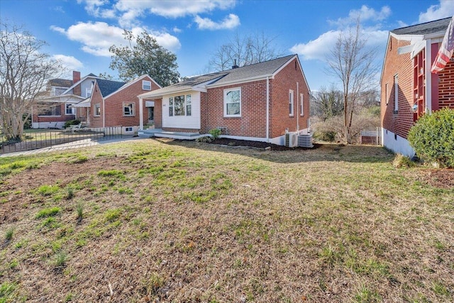 back of property with brick siding, central air condition unit, a yard, and fence