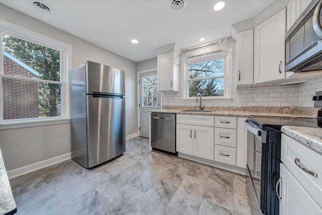 kitchen featuring white cabinetry, tasteful backsplash, appliances with stainless steel finishes, and a sink