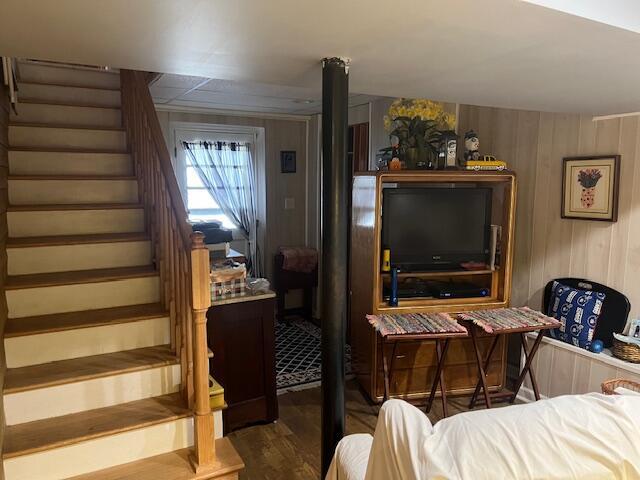 stairway with wooden walls and wood finished floors