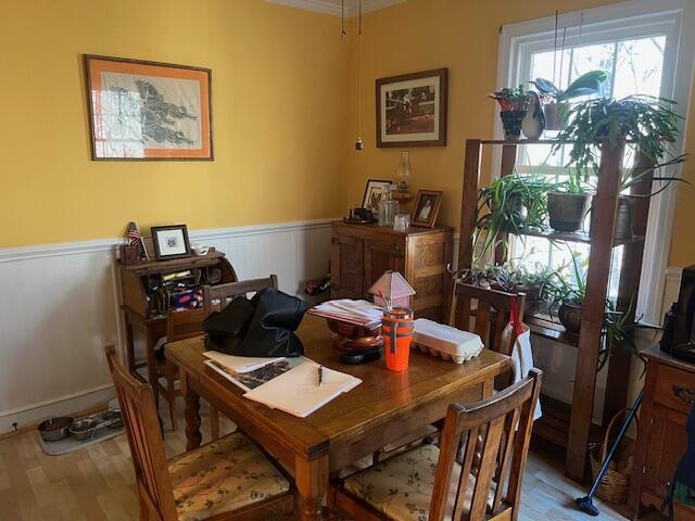 dining area with light wood-type flooring and a wainscoted wall