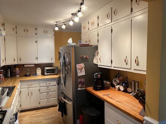 kitchen with white cabinets, freestanding refrigerator, and a toaster