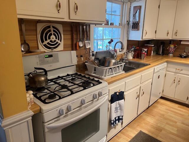 kitchen with light wood finished floors, white cabinets, white appliances, and light countertops