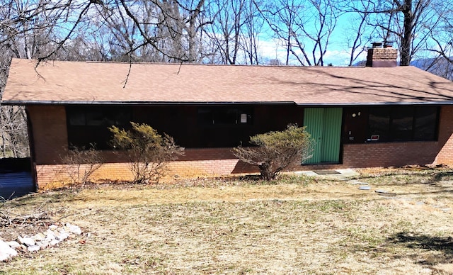 view of front facade featuring brick siding, roof with shingles, and a chimney