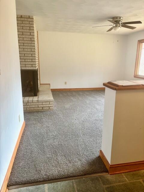 182 Dogwood Ln, Troutville, VA 24175 - unfurnished living room featuring carpet flooring, a brick fireplace, baseboards, and ceiling fan