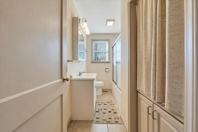 bathroom featuring tile patterned flooring, toilet, enclosed tub / shower combo, a textured ceiling, and vanity