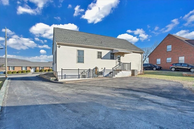 back of property featuring central air condition unit and roof with shingles