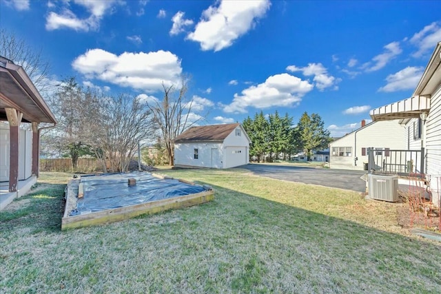 view of yard featuring an outbuilding, central AC unit, and fence