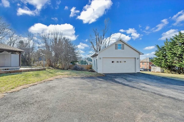 view of side of home with an outdoor structure, fence, a garage, and a lawn