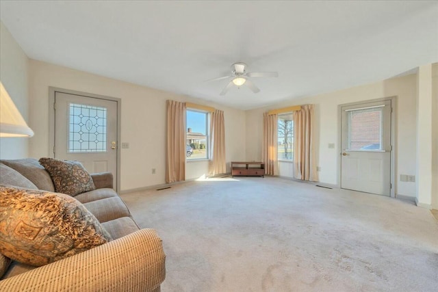 carpeted living room featuring visible vents, baseboards, and a ceiling fan