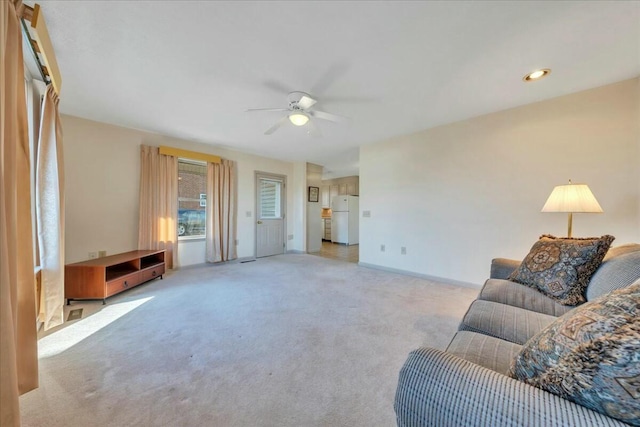 living room featuring baseboards, light colored carpet, and ceiling fan