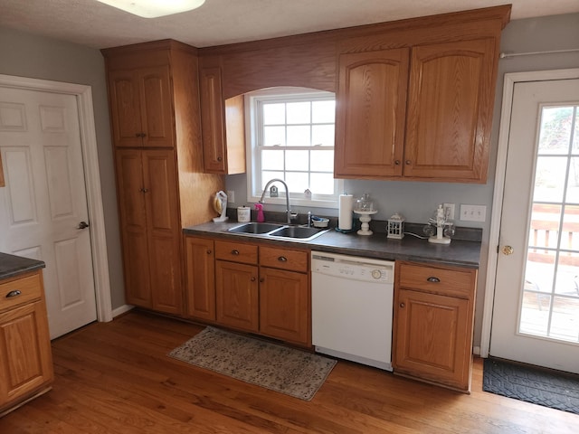 kitchen featuring a sink, dark countertops, brown cabinetry, and white dishwasher