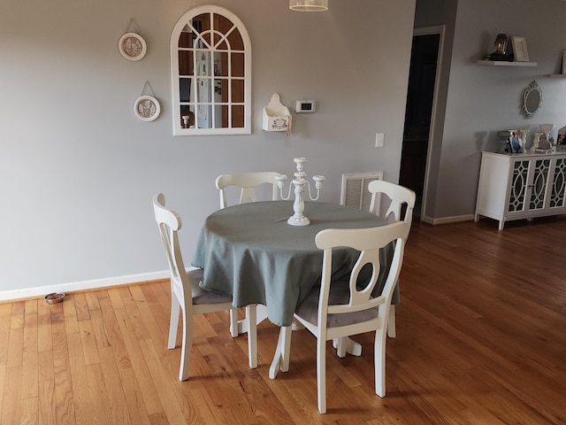 dining space with wood finished floors, visible vents, and baseboards