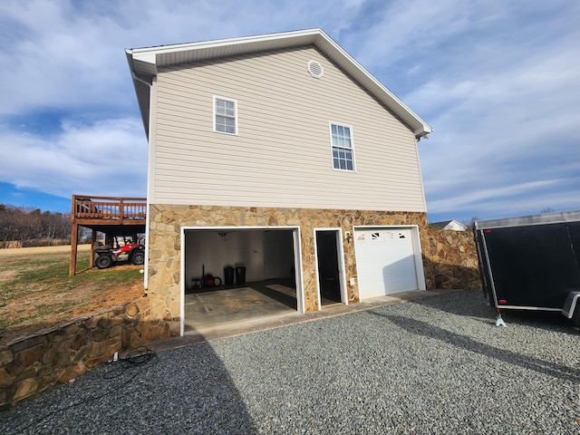 view of property exterior with stone siding, driveway, and a garage