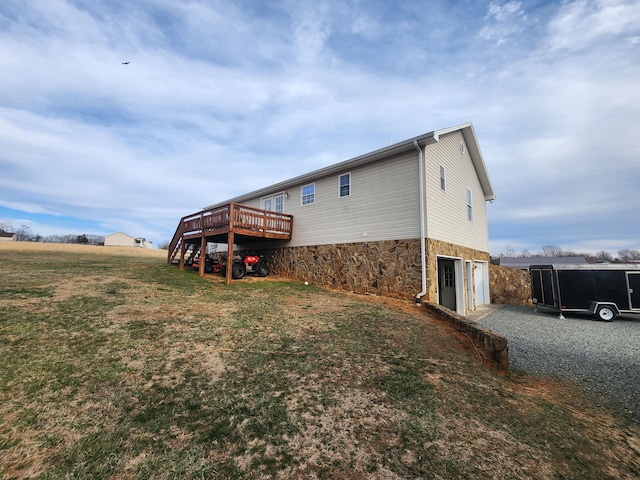 rear view of house with stairs, a deck, a garage, stone siding, and driveway