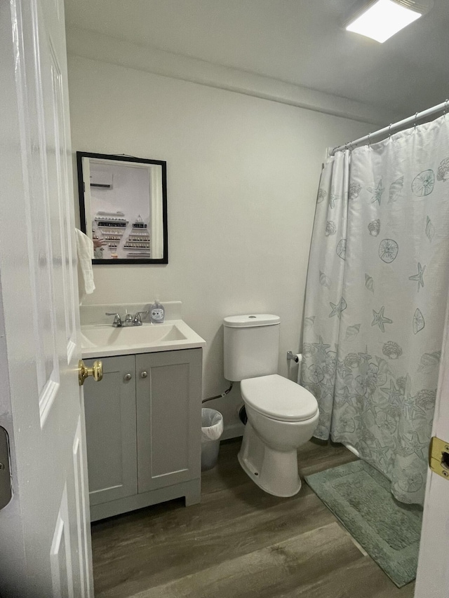 bathroom featuring a shower with curtain, toilet, wood finished floors, and vanity