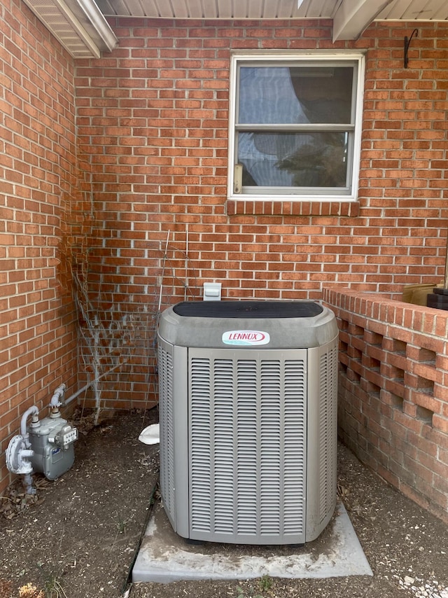 exterior details featuring brick siding, gas meter, and central AC