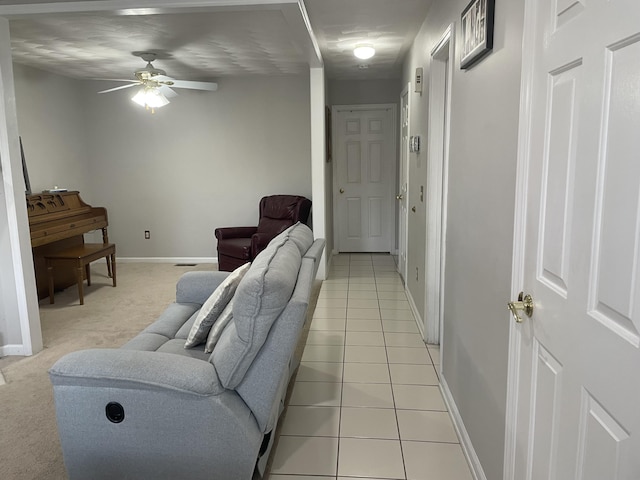 living room with light tile patterned floors, baseboards, light carpet, and a ceiling fan