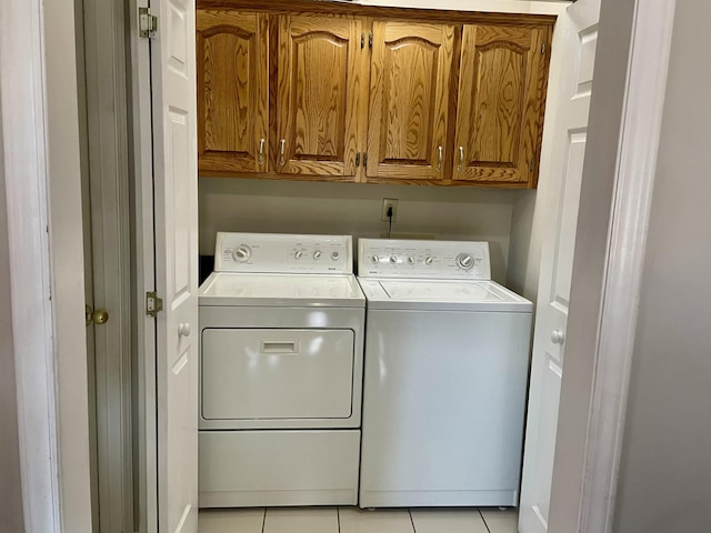 washroom with cabinet space, light tile patterned floors, and washer and dryer