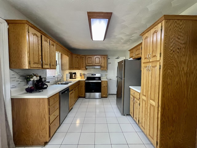 kitchen featuring brown cabinets, a sink, stainless steel appliances, light countertops, and light tile patterned floors