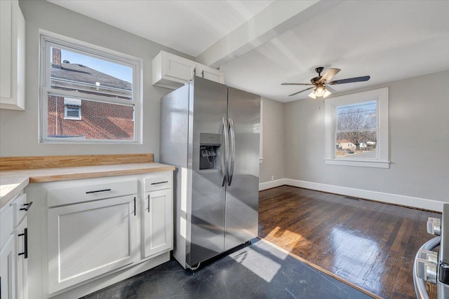 kitchen with white cabinets, plenty of natural light, baseboards, and stainless steel fridge