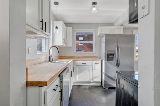 kitchen with pendant lighting, a sink, white cabinetry, appliances with stainless steel finishes, and wooden counters