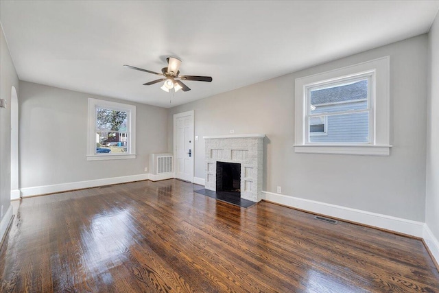 unfurnished living room featuring visible vents, ceiling fan, baseboards, a fireplace, and wood finished floors