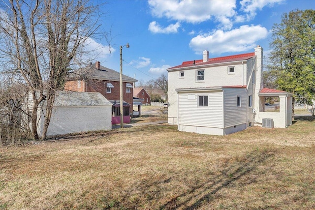 back of house with a lawn, cooling unit, and a chimney